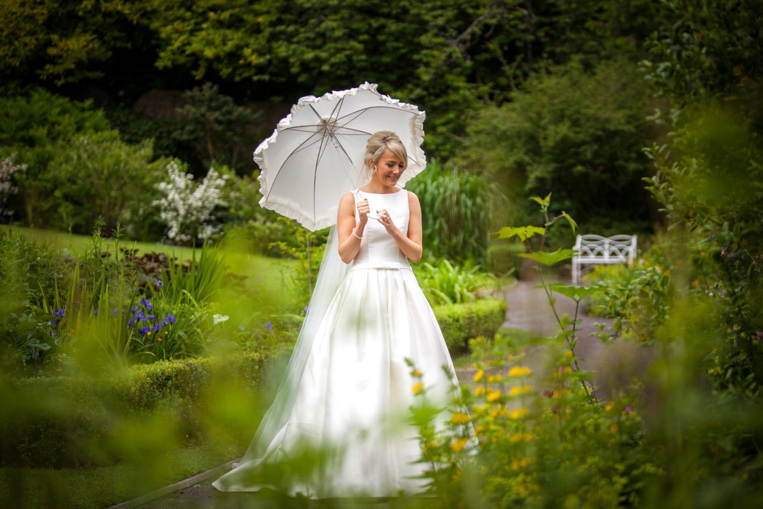 A bride in a wedding dress holding an umbrella, captured by a wedding photographer.